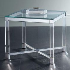 a glass table with metal legs and a tray on the top that is sitting on a hard wood floor