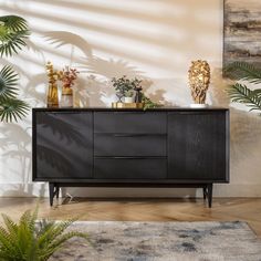 a black sideboard with plants and vases on top