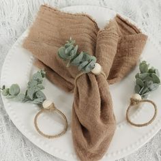 a white plate topped with two napkins and three succulents on top of each other