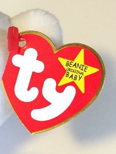 a red and white heart shaped tag with the words beanie babies baby on it