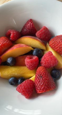 a white bowl filled with fresh fruit on top of a table