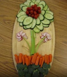 a wooden platter with vegetables cut into the shape of a flower and leaves on it