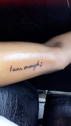 a woman's arm with the words i am enough tattooed on her left arm