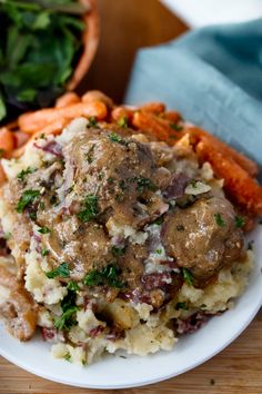 a white plate topped with meatballs and mashed potatoes on top of a wooden table