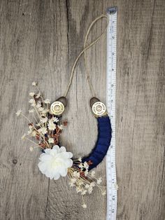 a white flower sitting on top of a wooden table next to a measuring tape and some flowers