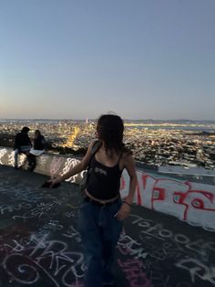 a woman standing on top of a roof with graffiti all over her and buildings in the background