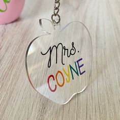 an apple shaped acrylic keychain with the words mrs coyle on it