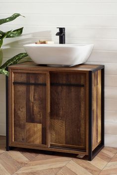 a bathroom sink sitting on top of a wooden cabinet next to a potted plant