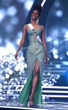 a woman in a green dress is walking down the runway with an award on her chest