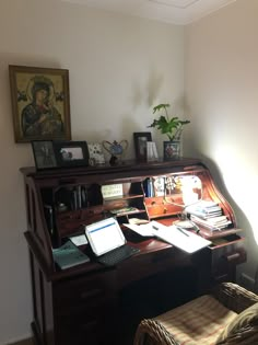 a wooden desk with a laptop on top of it next to a chair and potted plant