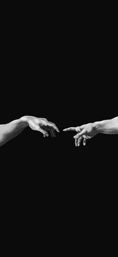 two hands reaching out towards each other in black and white, against a dark background