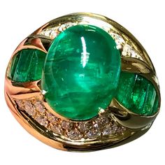 The pictures say it all… this ring is just magnificent! Crafted in 18K yellow gold, this beautiful cocktail ring is centered by an approximately 4.70ct natural cabochon emerald with absolutely electric color. Flanking the center stone stone are buff top natural calibrated emeralds that are a perfect match and weigh a total of 2cttw. Above and below the center Stone are pave set round diamonds ranging G-H in color and Vs1+ in clarity. Total approximate diamond weight is .60cttw. Ring is accompani Luxury Emerald Ring With Oval Cabochon And 17 Jewels, Luxury Oval Cabochon Emerald Ring With 17 Jewels, Luxury Green Cabochons, Luxury Oval Cabochon Emerald Ring, Luxury Yellow Gold Emerald Ring With Oval Cabochon, Elegant Cabochon Emerald Ring For Formal Occasions, Luxury High Luster Gemstones For Formal Occasions, Luxury Green Dome Ring For Formal Occasions, Unique Cabochon Emerald Ring For Formal Occasions