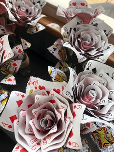 several playing cards and paper flowers on a table