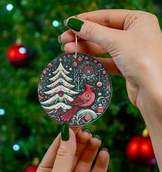 a person holding a christmas ornament in front of a christmas tree with lights