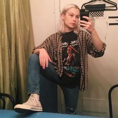 a woman taking a selfie in front of a mirror while sitting on a chair