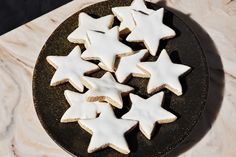 some white cookies are on a black plate and one is cut in to look like stars