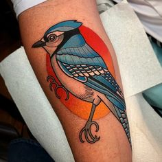 a blue bird tattoo on the right arm and leg with an orange circle in the background