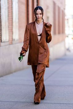 a woman walking down the street in a brown suit