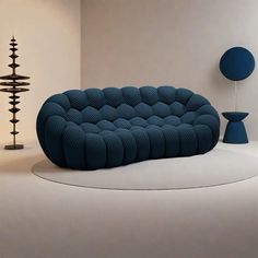 a blue couch sitting on top of a white floor next to a lamp and table