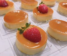 small desserts are arranged on clear trays with fresh strawberries in the middle