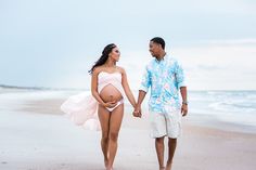 a pregnant woman walking on the beach with her husband