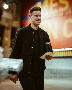 a man is walking down the street with a book in his hand