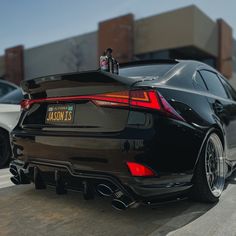 the rear end of a black car parked in a parking lot