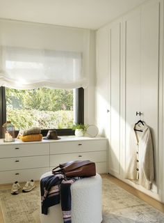 a bedroom with white walls and drawers, a window sill on the far wall