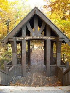 a small wooden structure in the middle of a forest with trees and leaves around it