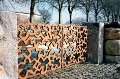 a large metal sculpture sitting next to a stone wall