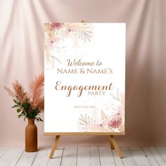 a welcome sign for an engagement party with pink flowers and greenery in the background