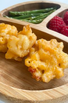 some food is on a wooden plate with green beans and raspberries in the background