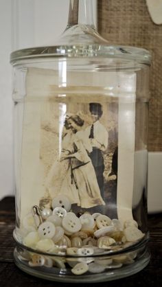 a glass jar filled with buttons on top of a table