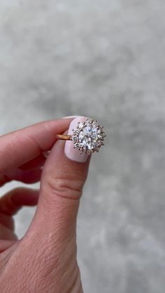 a woman's hand holding an engagement ring with a diamond center on the middle