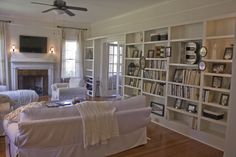 a living room filled with furniture and bookshelves next to a fire place in a fireplace