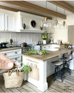 a kitchen with white cabinets and an island in the middle, filled with plants on it