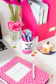 a pink desk with a laptop and flowers on it