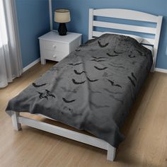 a bed with bats on it in a blue room next to a night stand and lamp