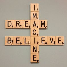 a cross made out of scrabble tiles with the words dream believe on it