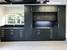 an empty kitchen with black cabinets and white floors