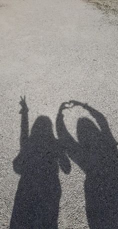 the shadow of two people holding their hands up