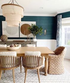 a dining room with blue walls and wooden table surrounded by wicker chairs in front of a large window