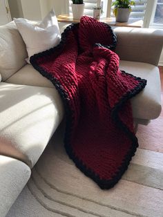 a red and black blanket sitting on top of a white couch