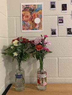 two vases filled with flowers sitting on top of a wooden table next to a wall