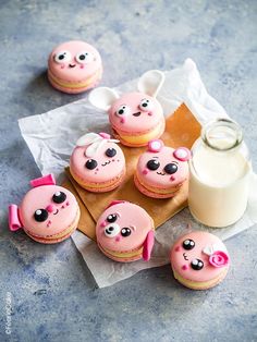 there are some pink cupcakes with eyes on them next to a bottle of milk