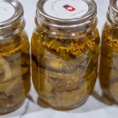 three jars filled with pickles sitting next to each other