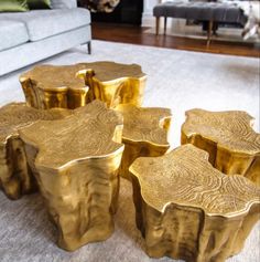 four pieces of gold colored wood sitting on top of a white rug in front of a couch