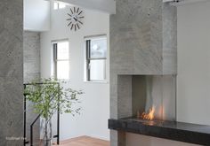 a living room with a fire place in the center and a clock on the wall