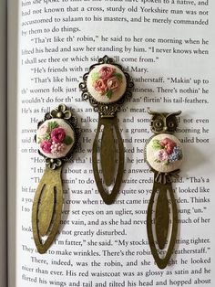 three pieces of brooch and earring sitting on top of an open book