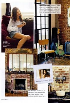 a woman sitting on a couch in front of a brick wall with pictures and guitar